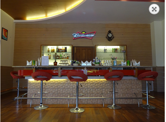 Bar interior with bottles and red chairs